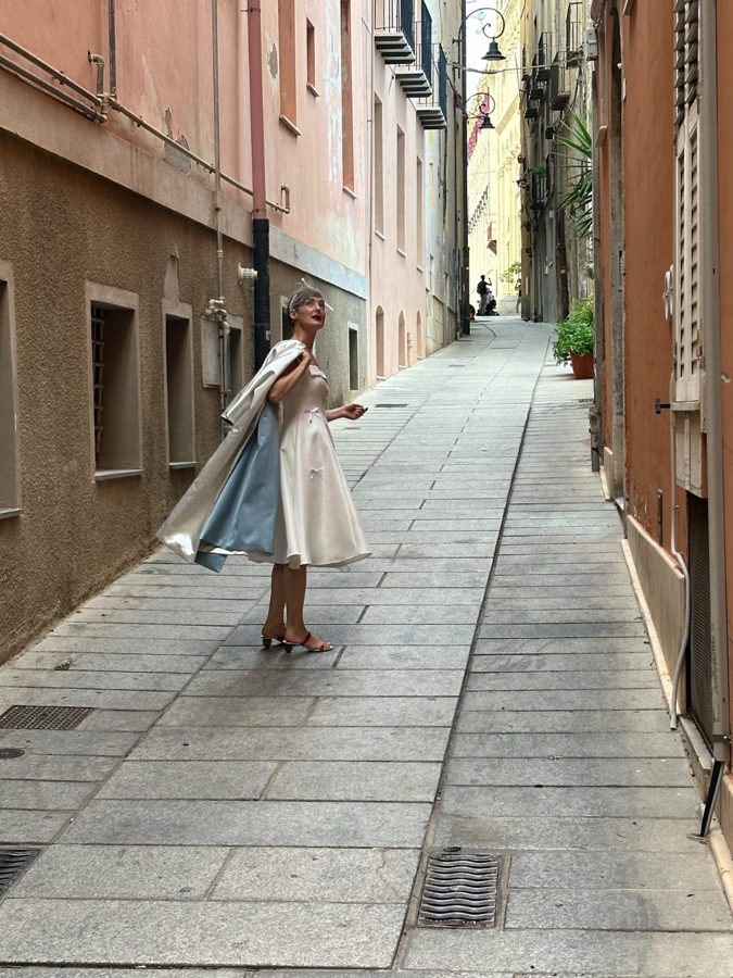 Bride twirling in white dress along a narrow Sardinian stone street.