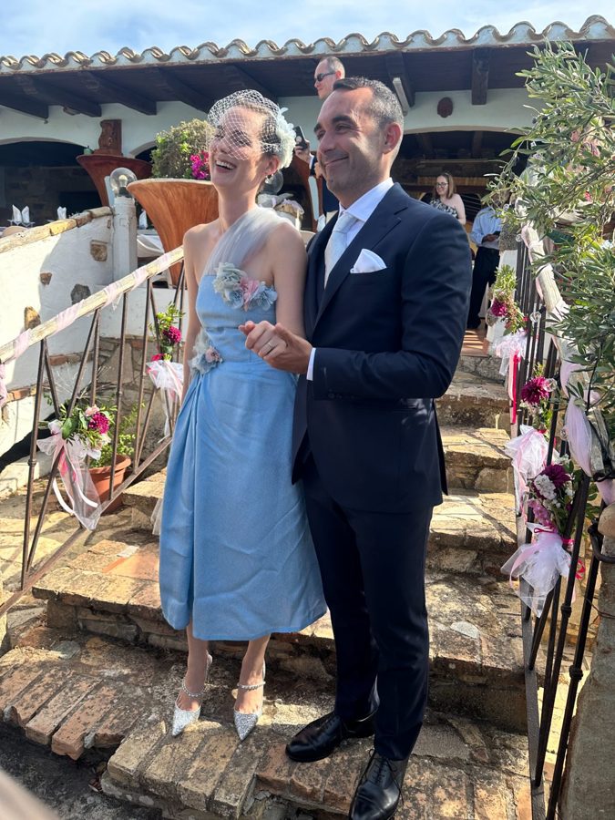 Bride and groom walk down rustic stone stairs decorated with flowers.