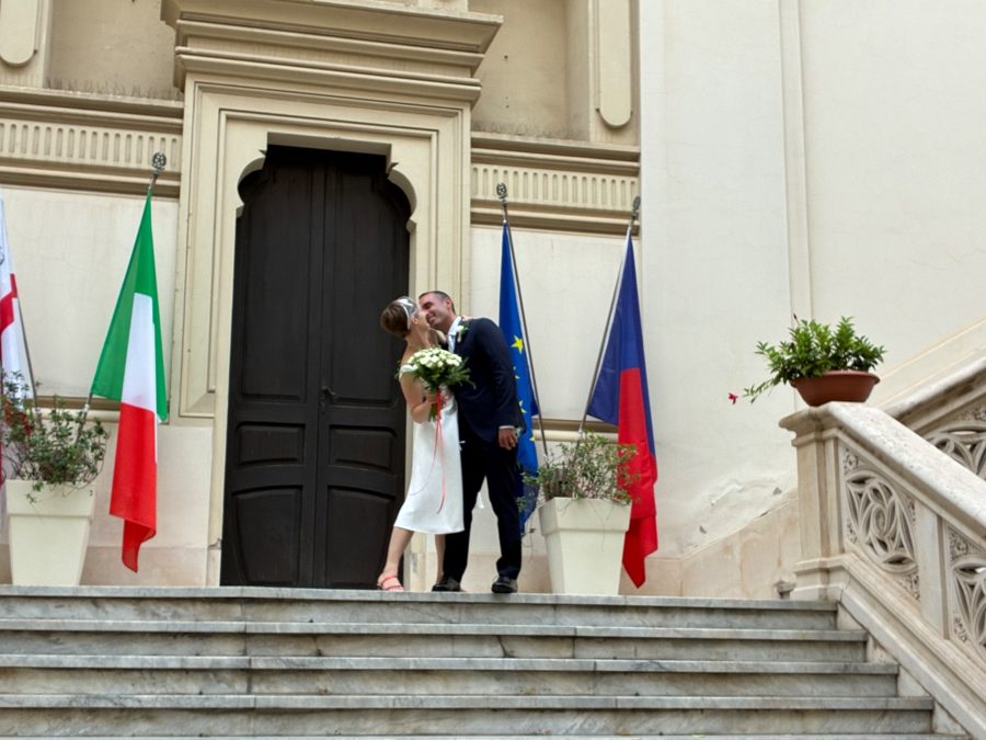 Bride and groom share a kiss on outdoor town hall steps.